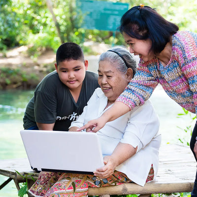 3 generations of family looking at a laptop and smiling. 