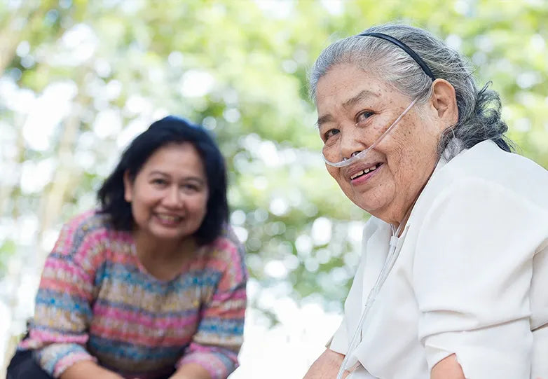 Old lady using nasal cannula and daughter smiling at the camera.