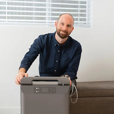 Man smiling sitting behind a Kingon P2 O5E stationary oxygen concentrator.