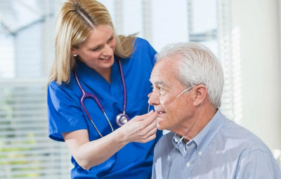 Nurse with an old man smiling while adjusting his nasal cannula.