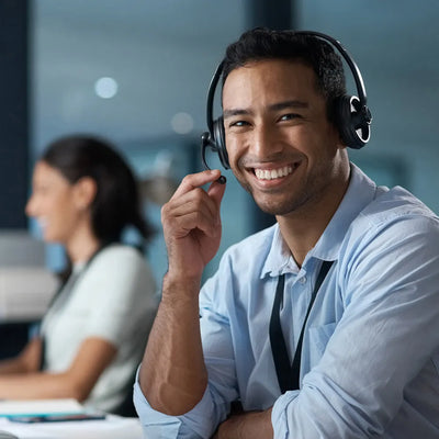 Man wearing a headset and smiling in an office setting.