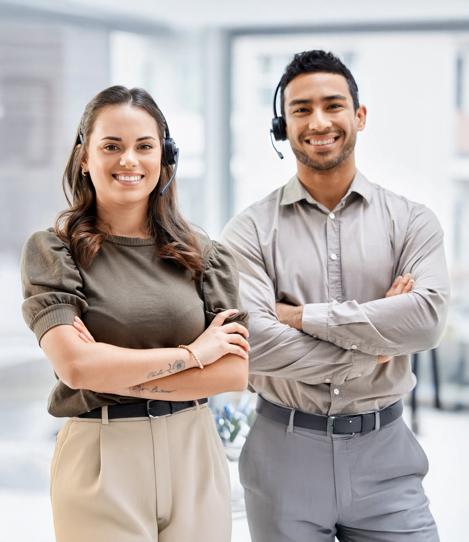 Two service agents smiling with their arms crossed in the office.
